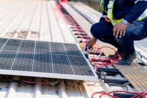 	
A worker in safety gear installs a solar panel on a rooftop, connecting red wires to the panel's terminals—exemplifying the expertise of Solar Installers Tangipahoa Parish.