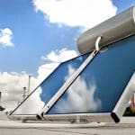 A Solar Water Heater with reflective panels and a storage tank is installed on the rooftop under a partly cloudy sky.